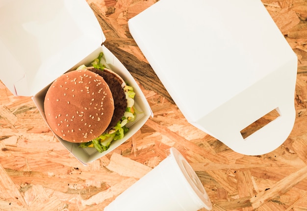 Free photo an overhead view of burger in package over the wooden background