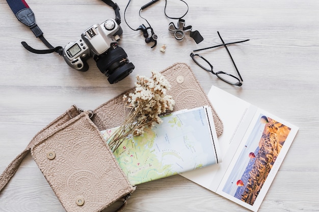 Free Photo overhead view of camera, handbag, and map on wooden desk