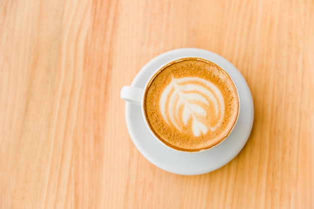 Free photo an overhead view of cappuccino coffee with art latte on wooden table