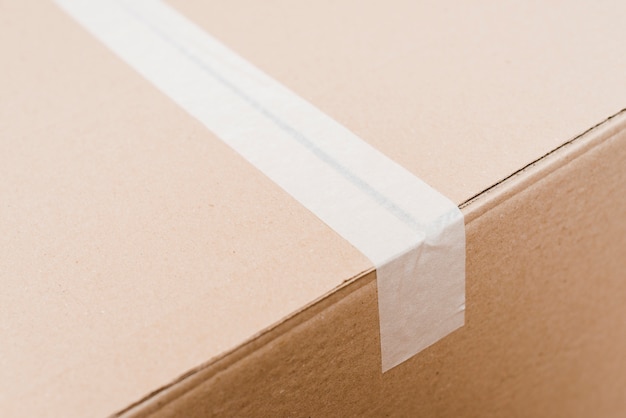 Free photo an overhead view of cardboard box sealed with white packing tape