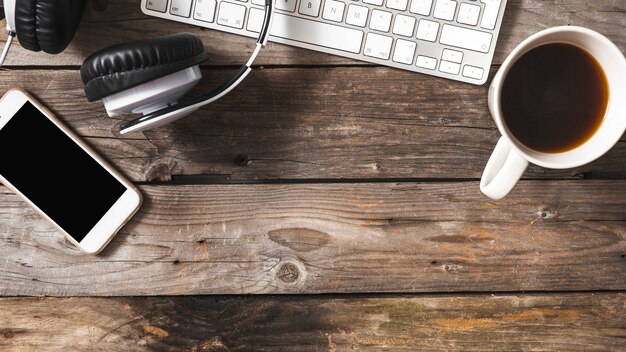 Overhead view of cellphone; headphone and keyboard with coffee cup