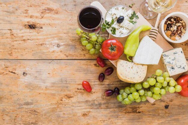 An overhead view of cheese blocks with grapes; tomatoes; green chili pepper and dried fruits