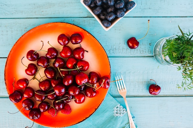 Free photo overhead view of cherries and blueberries on blue wooden desk