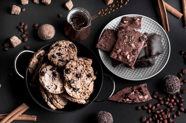 An overhead view of chocolate muesli cookies and chocolate on black background