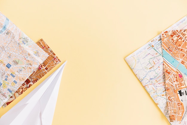 Free Photo an overhead view of cities road maps and paper airplane on colored background