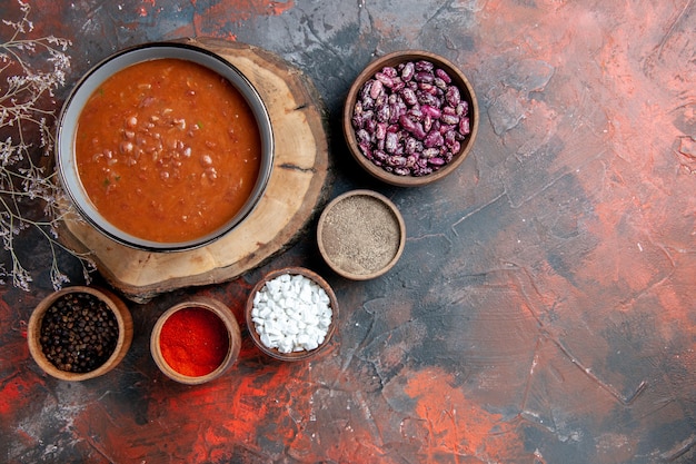 Free photo overhead view of classic tomato soup on wooden tray beans and different spices on mixed color table