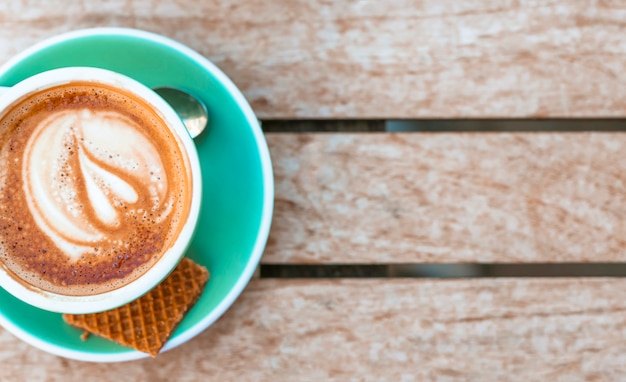 Free photo an overhead view of coffee cup with heart latte art on wooden table