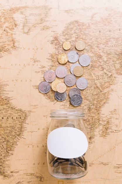 Free Photo overhead view of coins and an open jar on world map