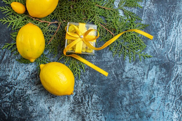 Overhead view of collection of natural organic fresh citrus fruits on fir branches and a gift box on dark background