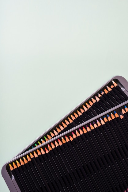 Free Photo an overhead view of colored pencils on an open metal box against gray background