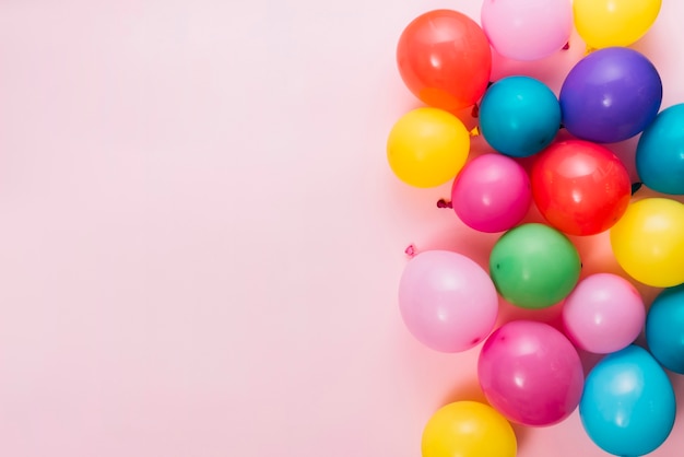 An overhead view of colorful balloons over pink background