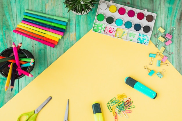 Overhead view of a colorful craft supplies and potted plant on wooden table