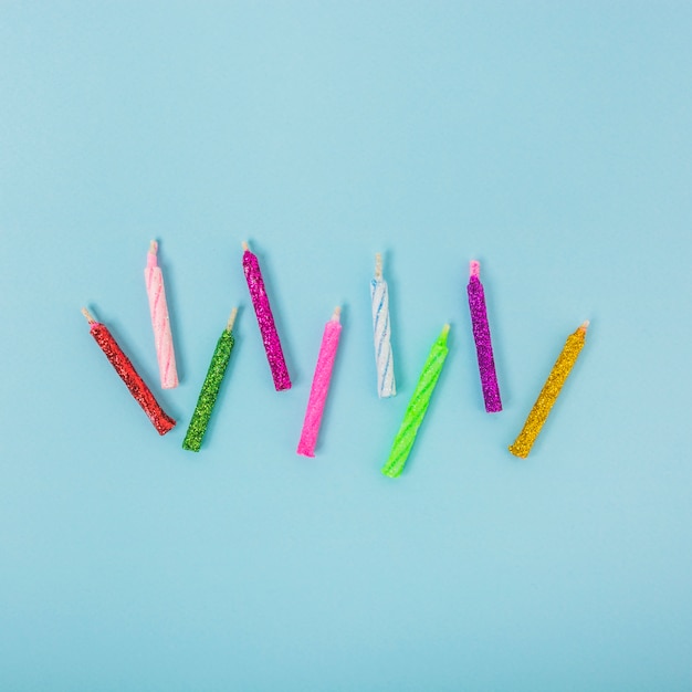 Free Photo overhead view of colorful shiny candles on blue backdrop