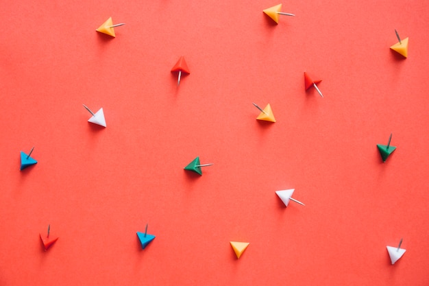 Free Photo overhead view of colorful triangular shaped push pins on orange background