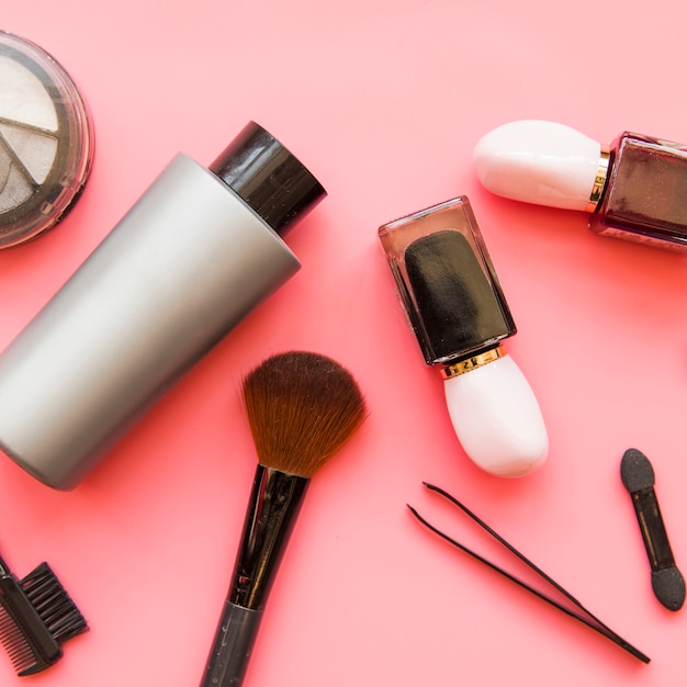 An overhead view of cosmetics makeup products on pink backdrop