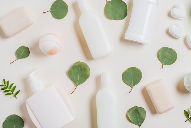 An overhead view of cosmetics products; soap; bath bomb and green leaves