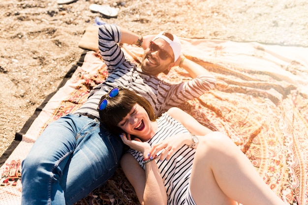 Free photo overhead view of couple lying on blanket at beach