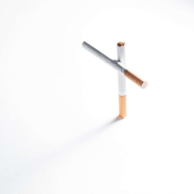 Free Photo overhead view of cross sign made from cigarette on white background