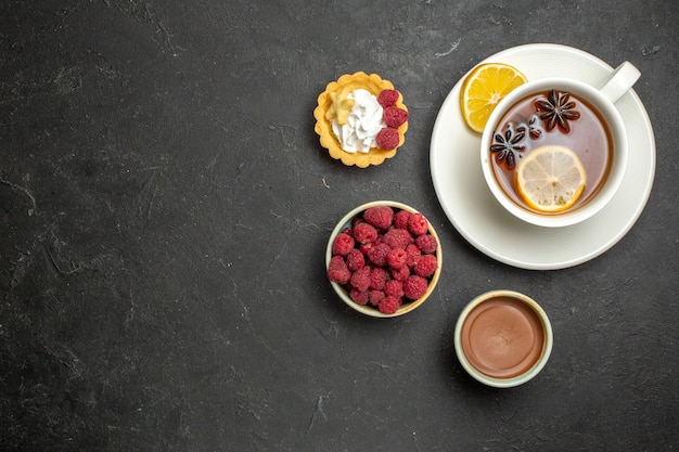 Free photo overhead view of a cup of black tea with lemon served with chocolate raspberry honey on dark background