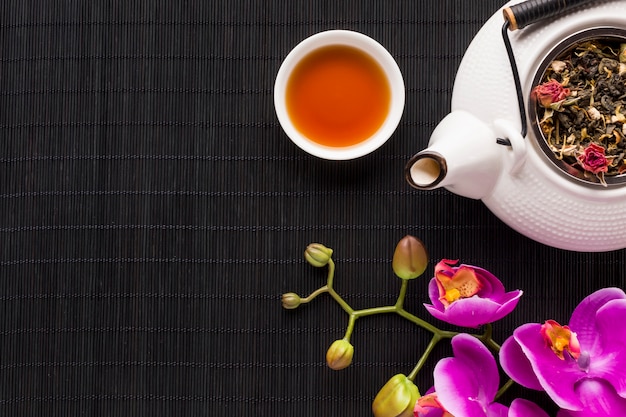 Free photo overhead view of delicate pink orchid flower and dry tea herb with teapot