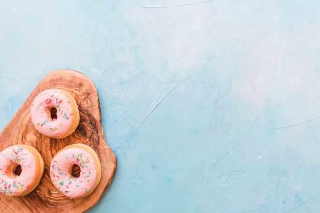 Overhead view of delicious donuts on wooden chopping board