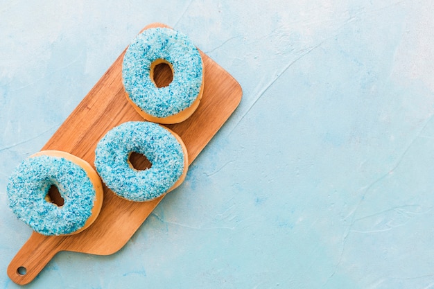 Overhead view of delicious fresh donuts on wooden chopping board