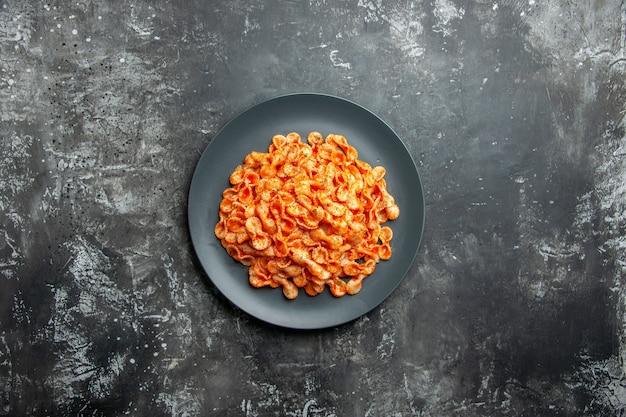 Overhead view of delicious pasta meal on a black plate for dinner on dark background