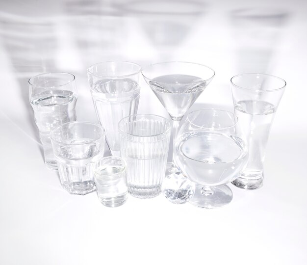 An overhead view of diamond with glasses of water with shadow on white backdrop