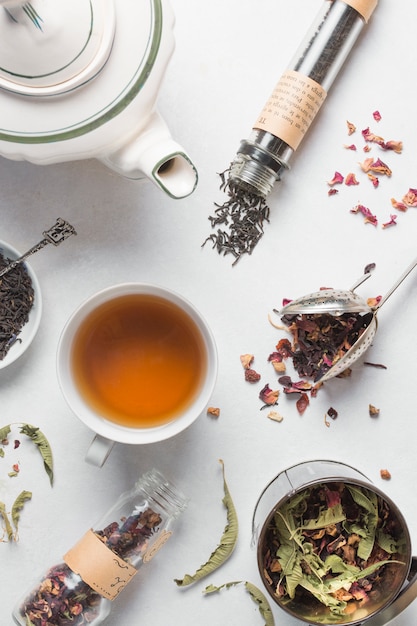 Free photo an overhead view of dried herbs with cup of tea and teapot on white background