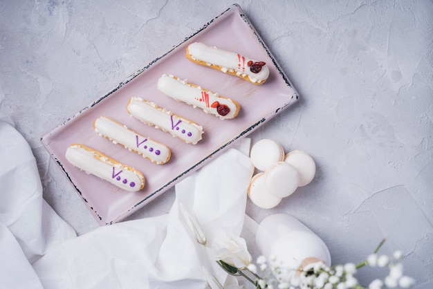 Free Photo an overhead view of eclair tray with macaroons on textured backdrop