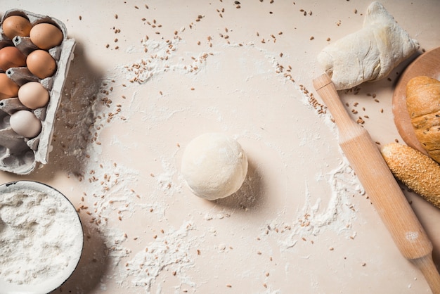 Free photo overhead view of eggs; flour; dough and baked breads on background