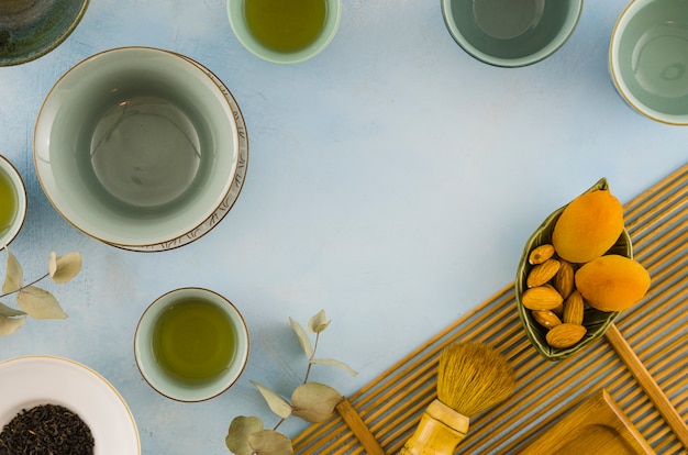 Free photo an overhead view of an empty tea cups with dried fruits and leaves on white background