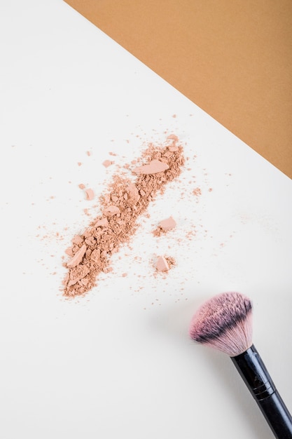 Overhead view of face powder and brush on dual colored background