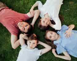 Free photo overhead view of family lying on grass and looking at camera