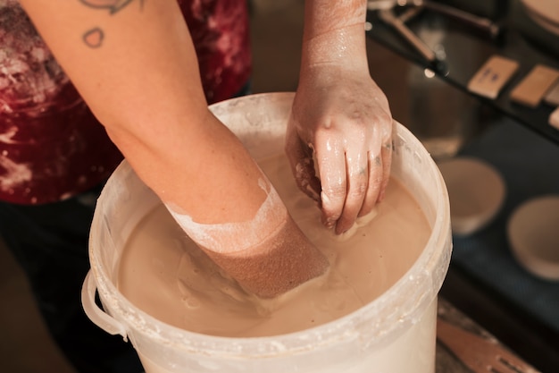 An overhead view of female potter's hand mixing the paint with hand