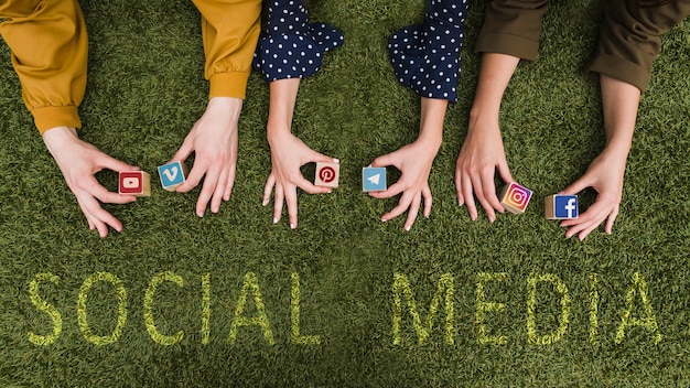 Free Photo overhead view of female's hand holding social network app symbol blocks on lawn