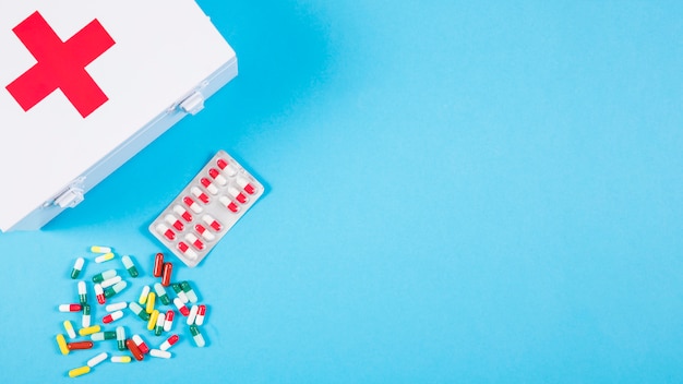 Free photo overhead view of first aid kit with colorful capsules on blue background