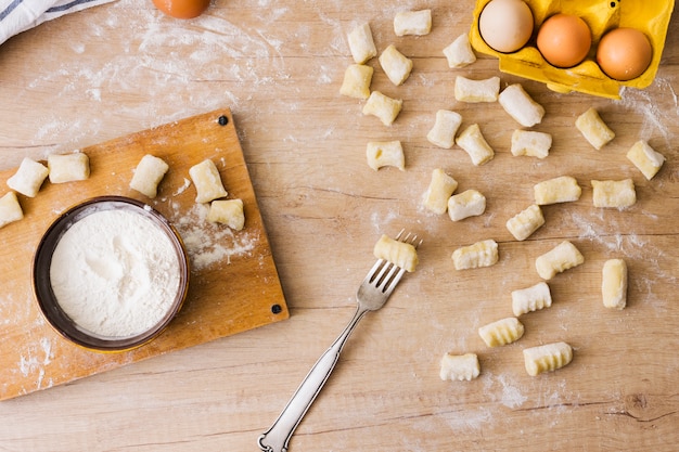 An overhead view of fork for preparing the fresh italian pasta gnocchi on wooden desk