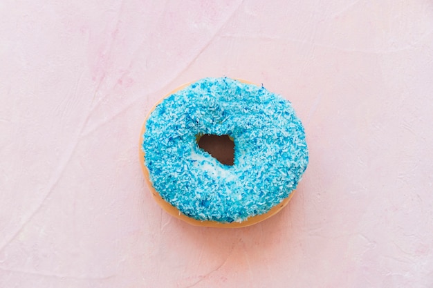 Overhead view of fresh blue donut on pink background