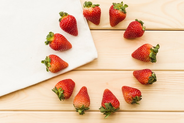 Free photo overhead view of fresh strawberries forming circles on wooden background