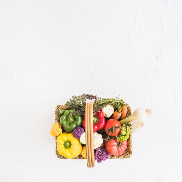 An overhead view of fresh vegetable in the basket over the textured background