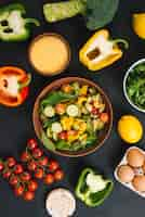 Free photo an overhead view of fresh vegetable salad; eggs; puffed rice cake and polenta on black concrete backdrop