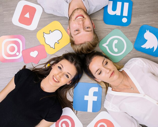 Overhead view of friends lying on backdrop with social media icons