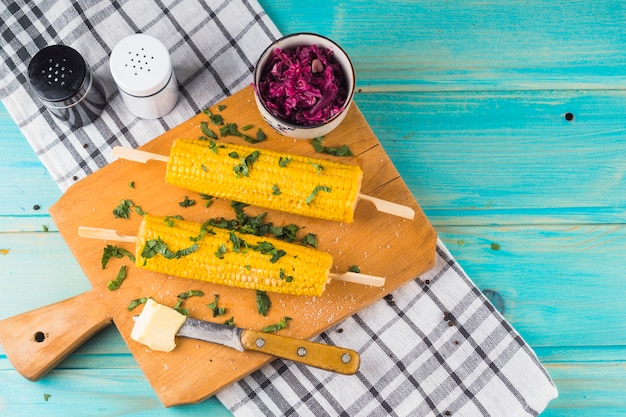 Free photo overhead view of a garnish corn with butter on wooden chopping board