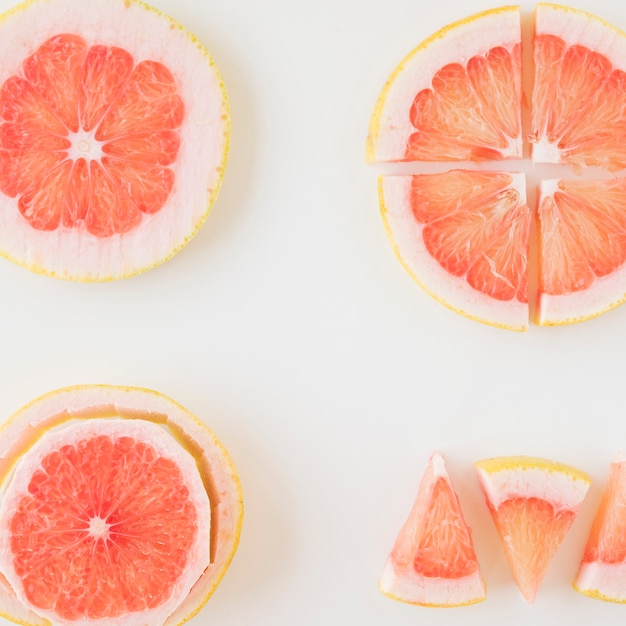 Free photo an overhead view of grapefruit cut in different shape and slice over the white backdrop