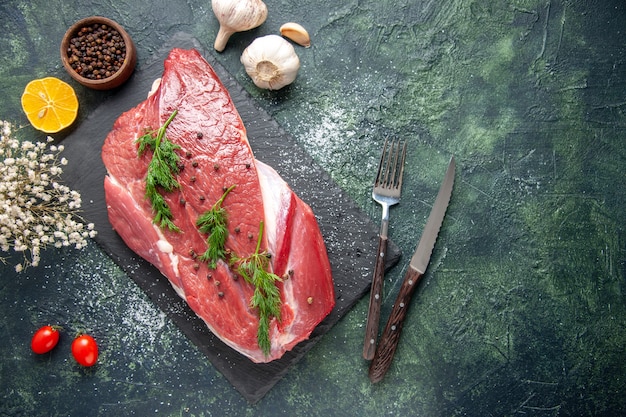 Free photo overhead view of green on fresh red raw meat on cutting board and pepper lemon flower on green black mix color background