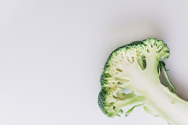 An overhead view of halved broccoli on the corner of the white background