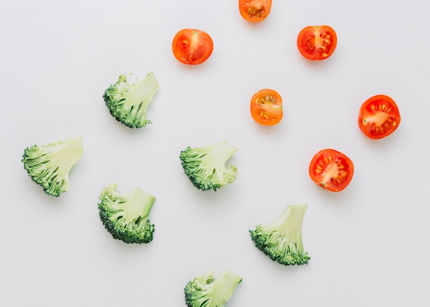 Free Photo an overhead view of halved cherry tomatoes and broccoli on white backdrop