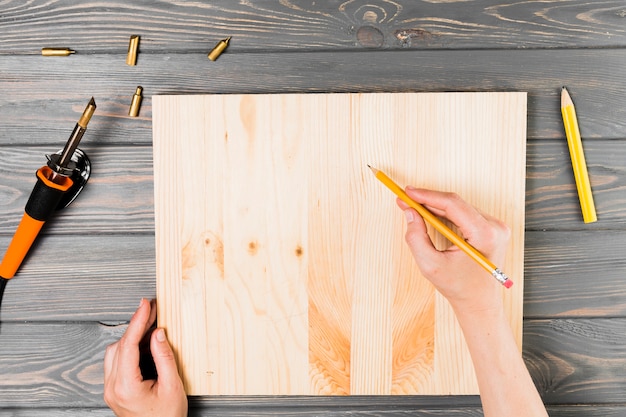 Overhead view of hand drawing on wooden board over table