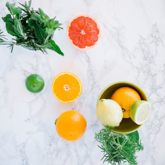 Overhead view of healthy citrus fruits and rosemary on marble